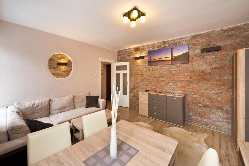 a living room with a table and a brick wall at Gdańskie Apartamenty - Apartament Szeroka in Gdańsk