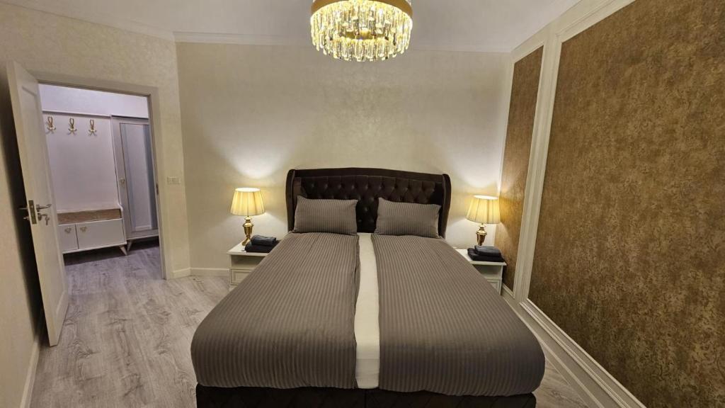 a bedroom with a large bed with two lamps and a chandelier at Book your Luxury Cozy Apartment in City Center Suceava in Suceava