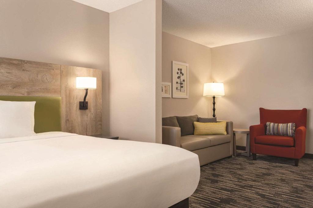 una habitación de hotel con una cama y una silla en Country Inn &amp; Suites by Radisson, St Cloud East, MN, en Saint Cloud