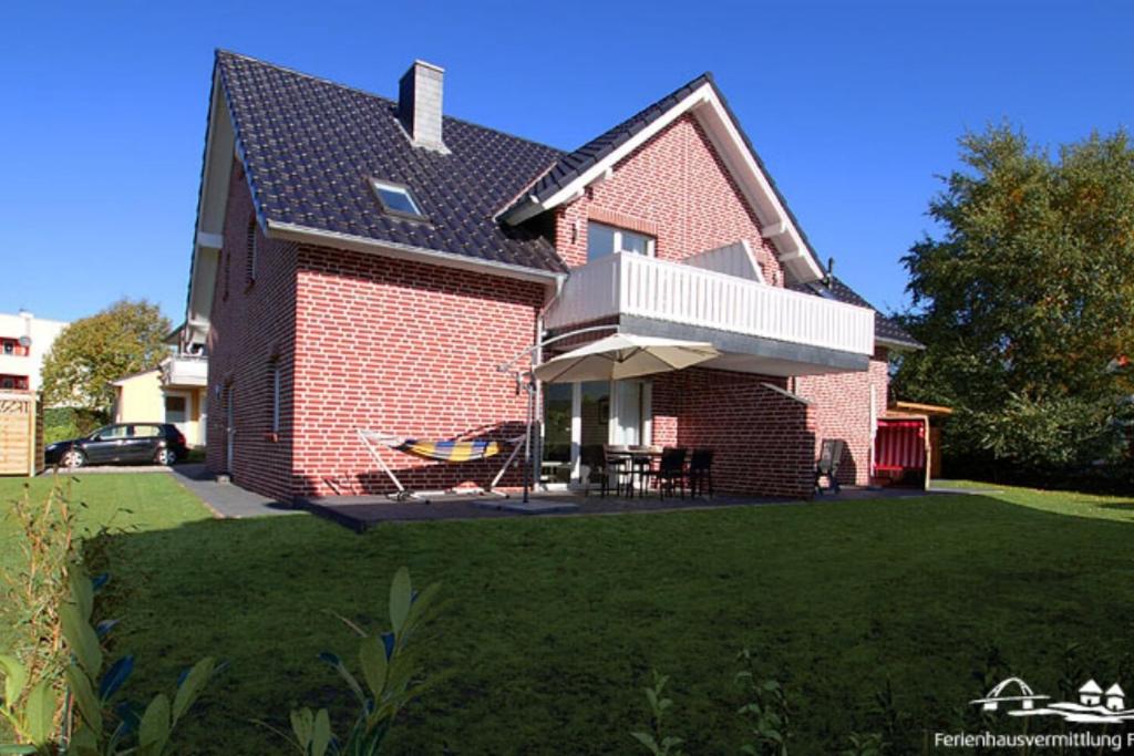 Casa de ladrillo rojo con balcón en un patio en 42 Ferienwohnung im Birkenweg 1c EG, en Burg auf Fehmarn