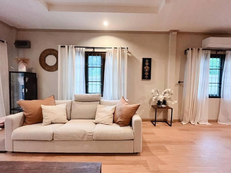 a living room with a white couch and two windows at Charming Getaway in Koh Chang in Ko Chang