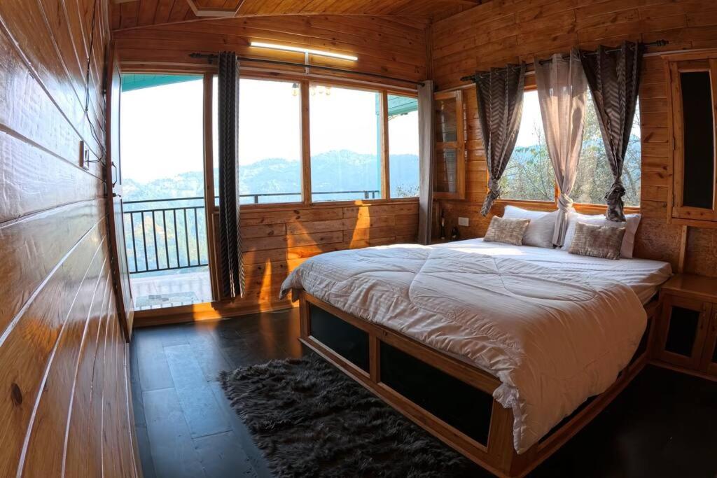 a bedroom with a bed in a room with windows at Cabin by The Woods - Mukteshwar - Nature - Romantic - Secluded in Mukteswar