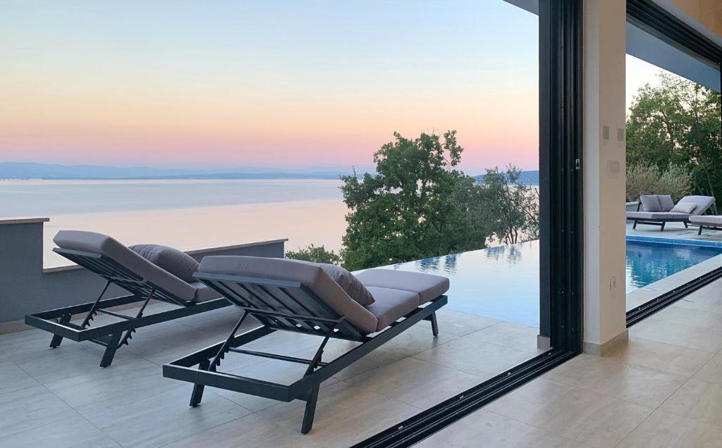 two lounge chairs on a balcony with a view of the water at Sky Pool VILLA MEDVEJA in Medveja