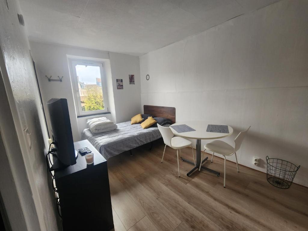 une chambre avec un lit et une table avec des chaises dans l'établissement Loft cosy au calme, à Montbéliard