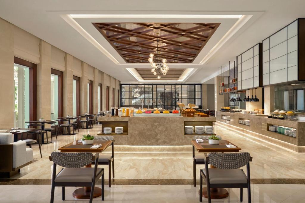A bright buffet-style dining room with a central food counter and neatly set tables.