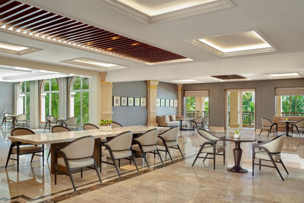An airy hotel lounge with extensive seating, garden-facing windows and decorative lighting.
