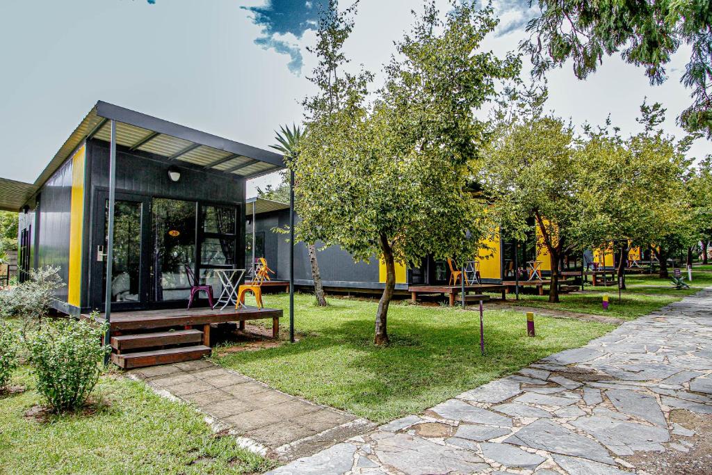 a yellow and black building with benches and trees at SleepOver Lanseria in Lanseria