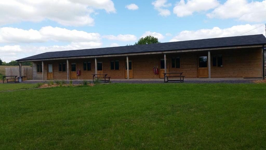 a building with benches in front of a grass field at Cowbridge Cabins in Cowbridge