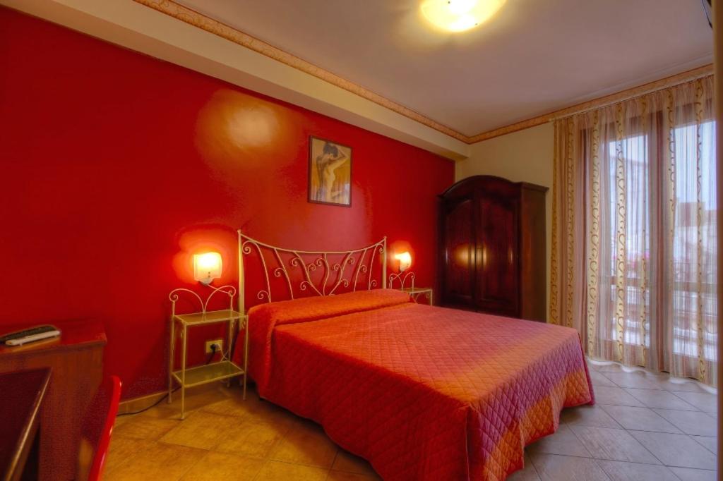 1 dormitorio rojo con 1 cama y pared roja en B&B Epos Acitrezza, en Aci Trezza