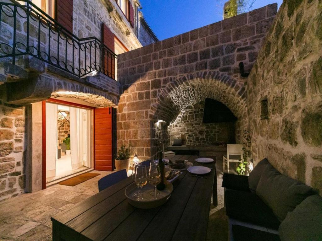 a patio with a wooden table in a brick building at Stylish Holiday Home Vis Center in Vis