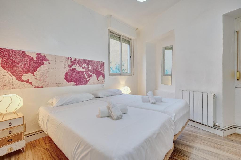 two white beds in a room with a map on the wall at Casa De Esme ll in Haro