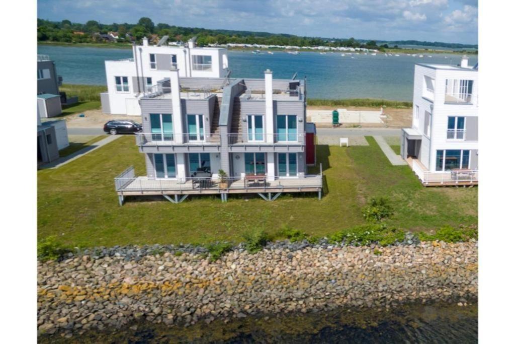 una gran casa blanca en un césped junto al agua en Schleivilla, en Olpenitz