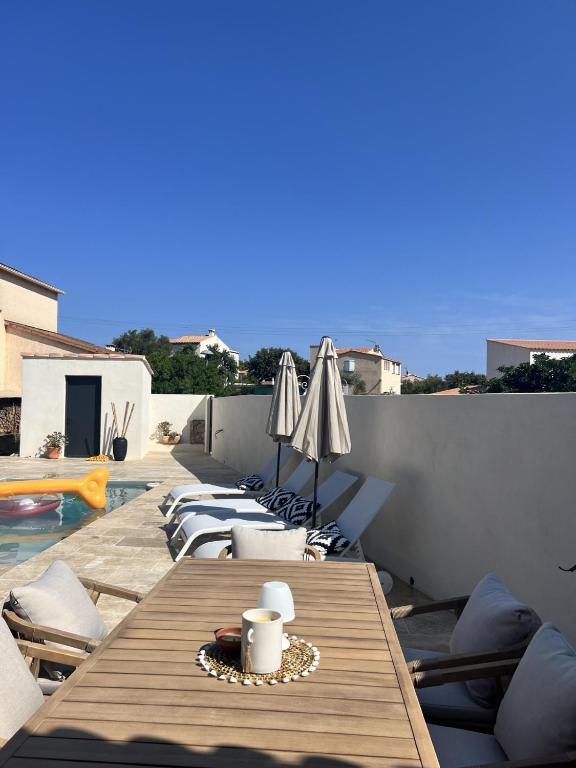 - une table en bois avec des chaises et des parasols à côté de la piscine dans l'établissement Superbe maison avec piscine, à Monticello