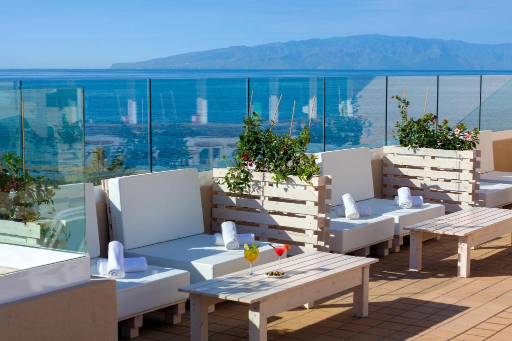 a row of tables and benches on a balcony at Aparthotel Los Dragos del Sur in Puerto de Santiago