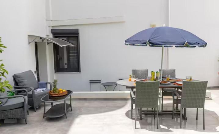 a patio with a table with an umbrella and chairs at Airport and Sea apartment in Porto Rafti