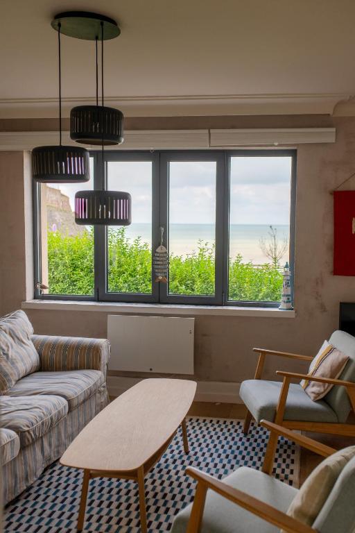 - un salon avec un canapé, une table et des fenêtres dans l'établissement Histoires d'Ault - maison vue mer et jardin, à Ault