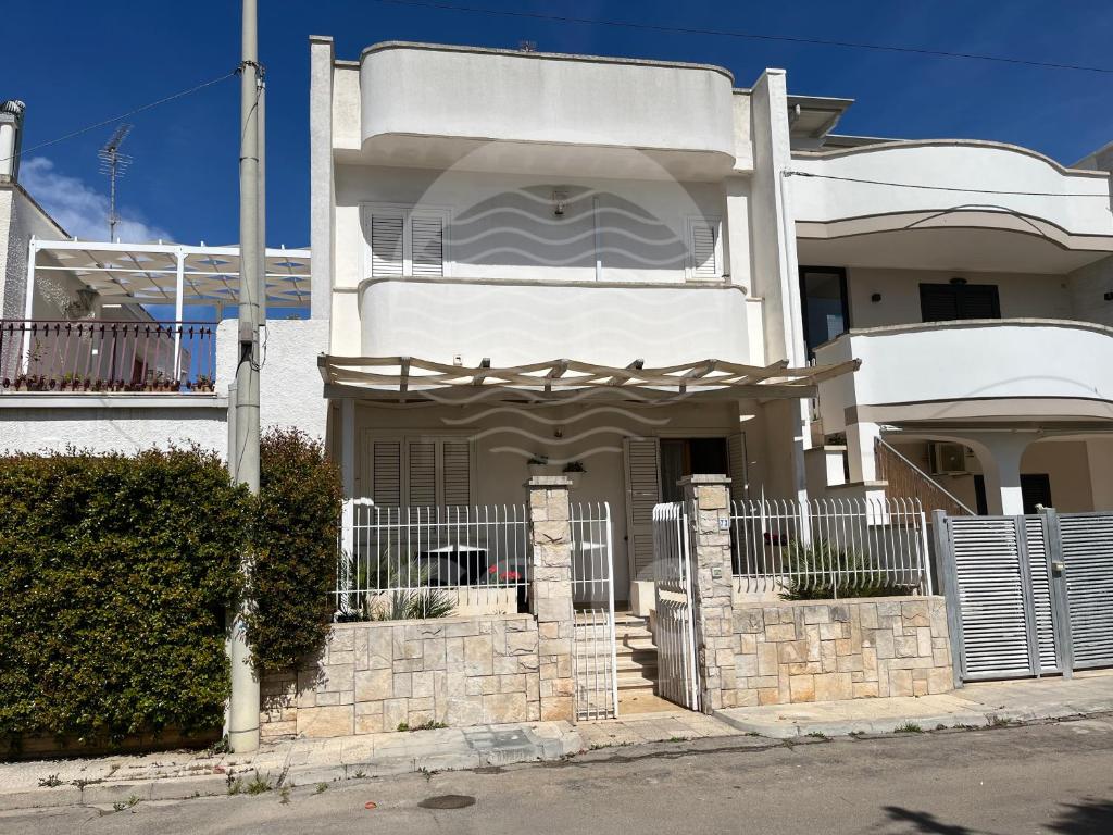a white house with a fence in front of it at Casa Estela By Cala Salento in Porto Cesareo