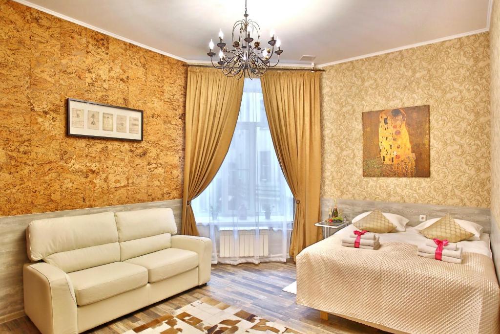 uma sala de estar com um sofá, uma cama e um lustre em Avangard Hotel em São Petersburgo