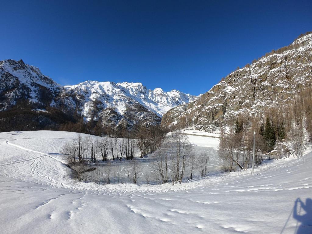 a snow covered slope with trees and mountains in the background at MCX Vacation Rental - MAISON LOZ duplex in typical village in Valtournenche with modern comforts just 2 minutes from the cable cars! in Valtournenche