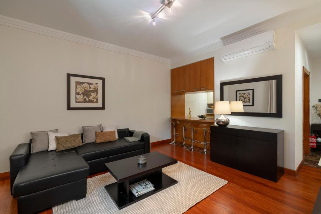 a living room with a black couch and a table at Arriaga Residence I by An Island Apart in Funchal