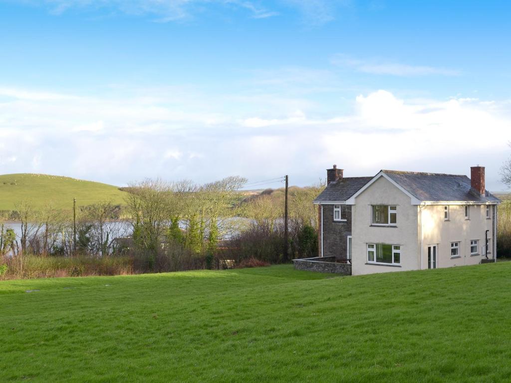 a white house on a hill with a green field at Tregunna Cottage in Wadebridge
