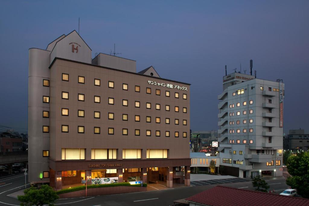 un edificio de hotel y un edificio alto en Hotel Sunshine Tokushima, en Tokushima
