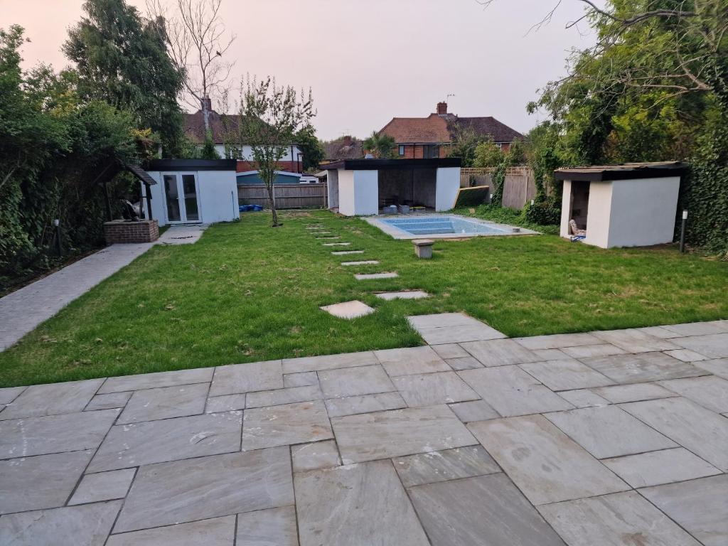 a backyard with a patio and a yard with a pool at A home away from home in Ash