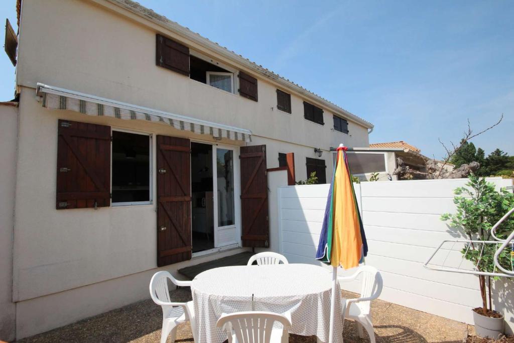 un patio avec une table et des chaises et un bâtiment dans l'établissement Maison T2 cabine 4 couchages, terrasse cloturée, résidence Sun village avec piscine commune, 300m de la plage à PORTIRAGNES PLAGE LRSUNR6, à Portiragnes