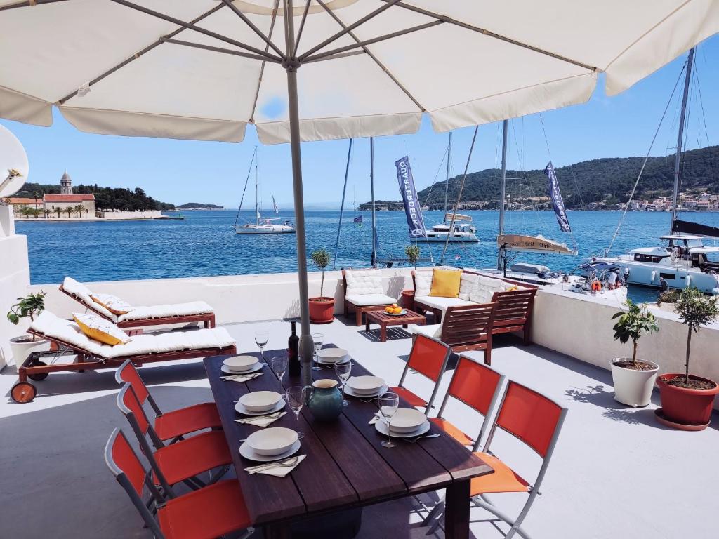 a table with chairs and an umbrella on the deck of a boat at Waterfront House Carolina in Vis