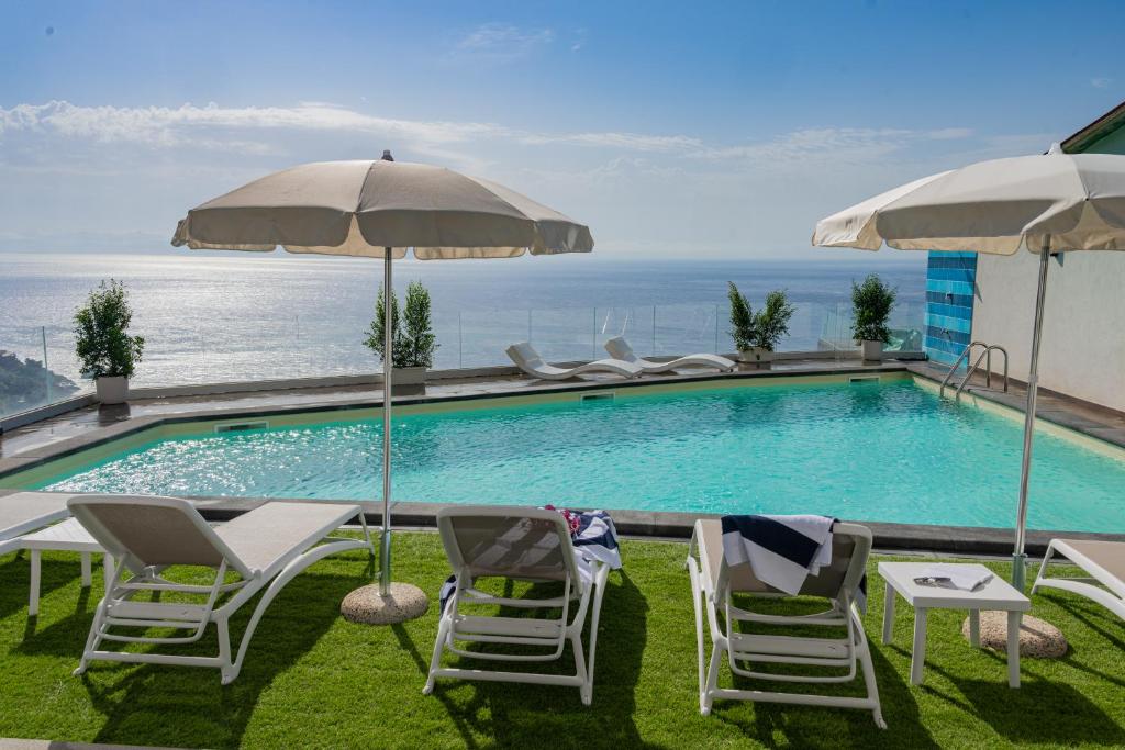 a swimming pool with chairs and an umbrella at Villa Horizonte Taormina in Taormina