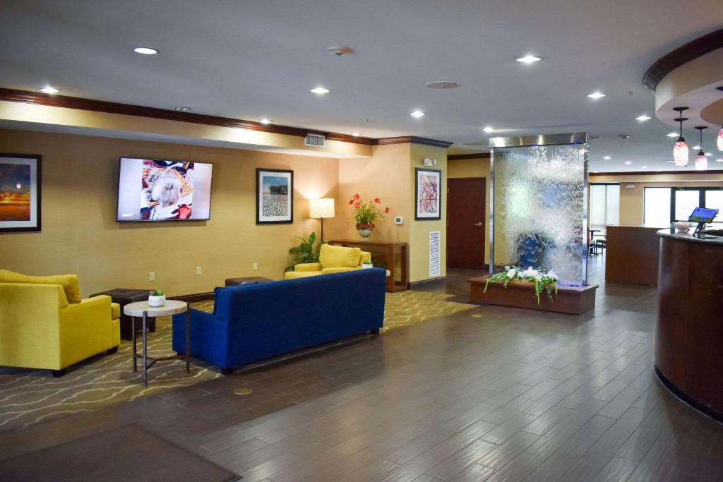a lobby of a hospital with a blue couch and yellow chairs at Comfort Suites in Forrest City
