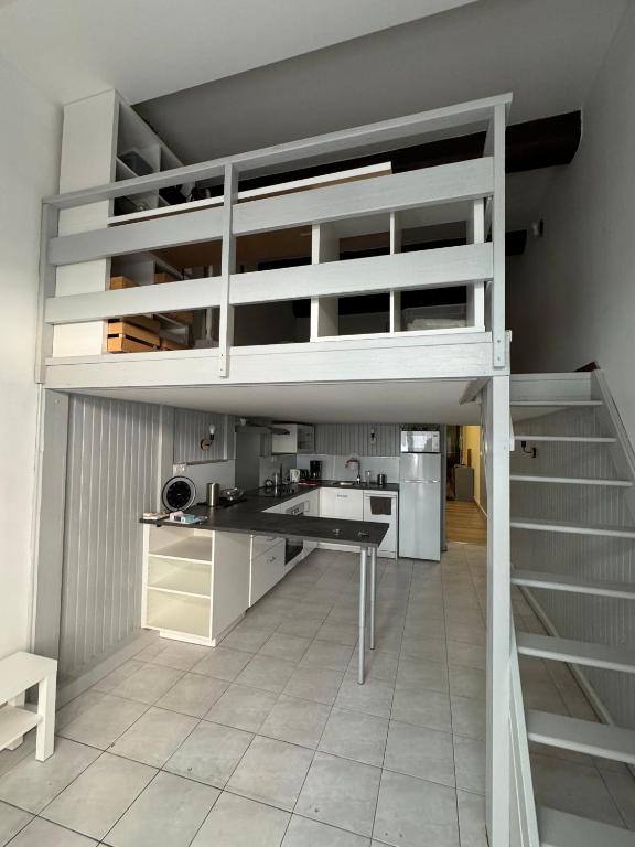 Ce lit superposé blanc se trouve dans un dortoir doté d'une cuisine. dans l'établissement Au pied des Halles - 46m2 en centre ville - 1 chambre et 1 mezzanine - tout confort, à Sète
