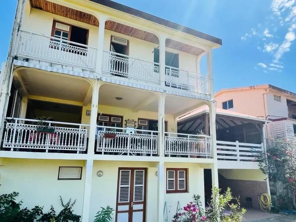 a white building with white balconies and white railings at Maison charmante avec vue sur la mer et montagnes, Les Anses-d'Arlet. in Les Anses-dʼArlets