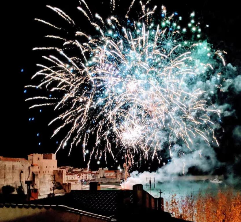 un feu d'artifice dans le ciel au-dessus d'une ville dans l'établissement Le Mirador Duplex avec vue mer, clim et garage, à Collioure