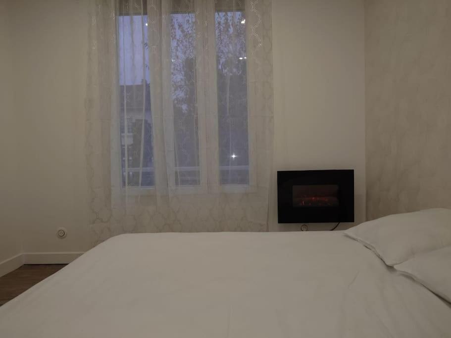 une chambre blanche avec un lit et une cheminée dans l'établissement Cosy Appartement proche Paris, à Villeparisis