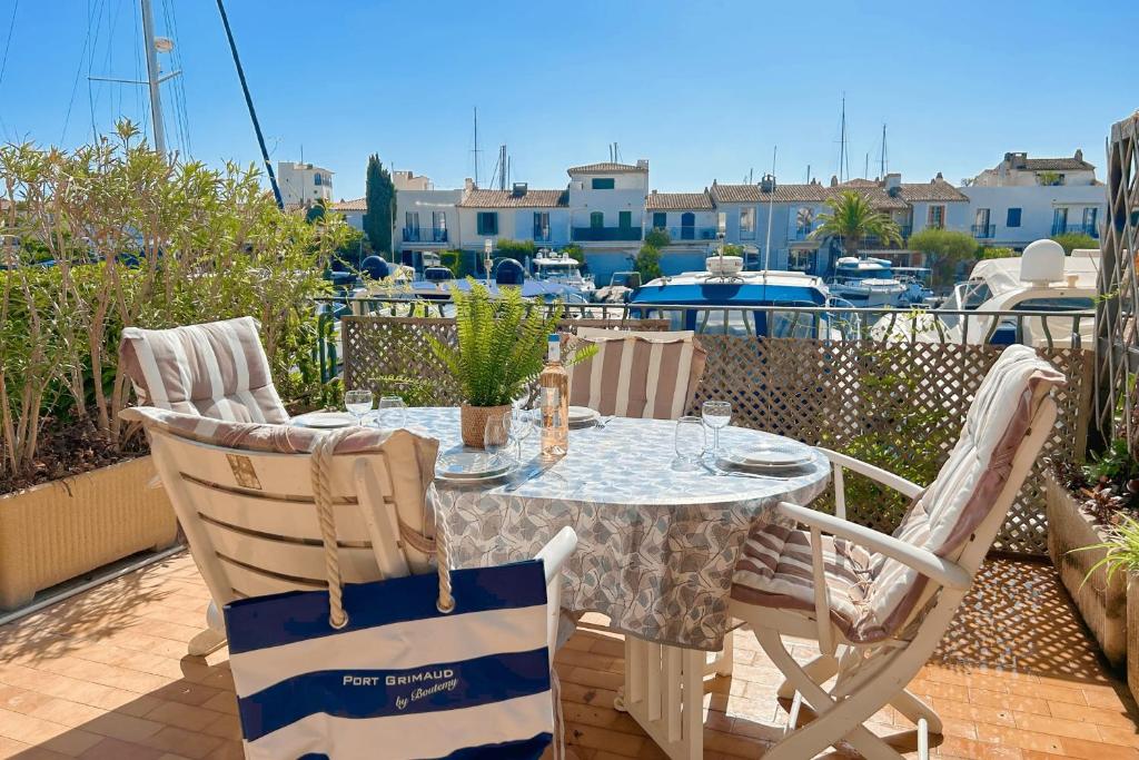 une table et des chaises sur une terrasse avec un port de plaisance dans l'établissement Renovated 2 room apartment - AC and terrace, à Grimaud