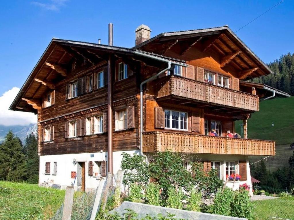 ein großes Holzhaus mit Balkon auf einem Hügel in der Unterkunft Apartment Gilbachhöckli 2 by Interhome in Adelboden