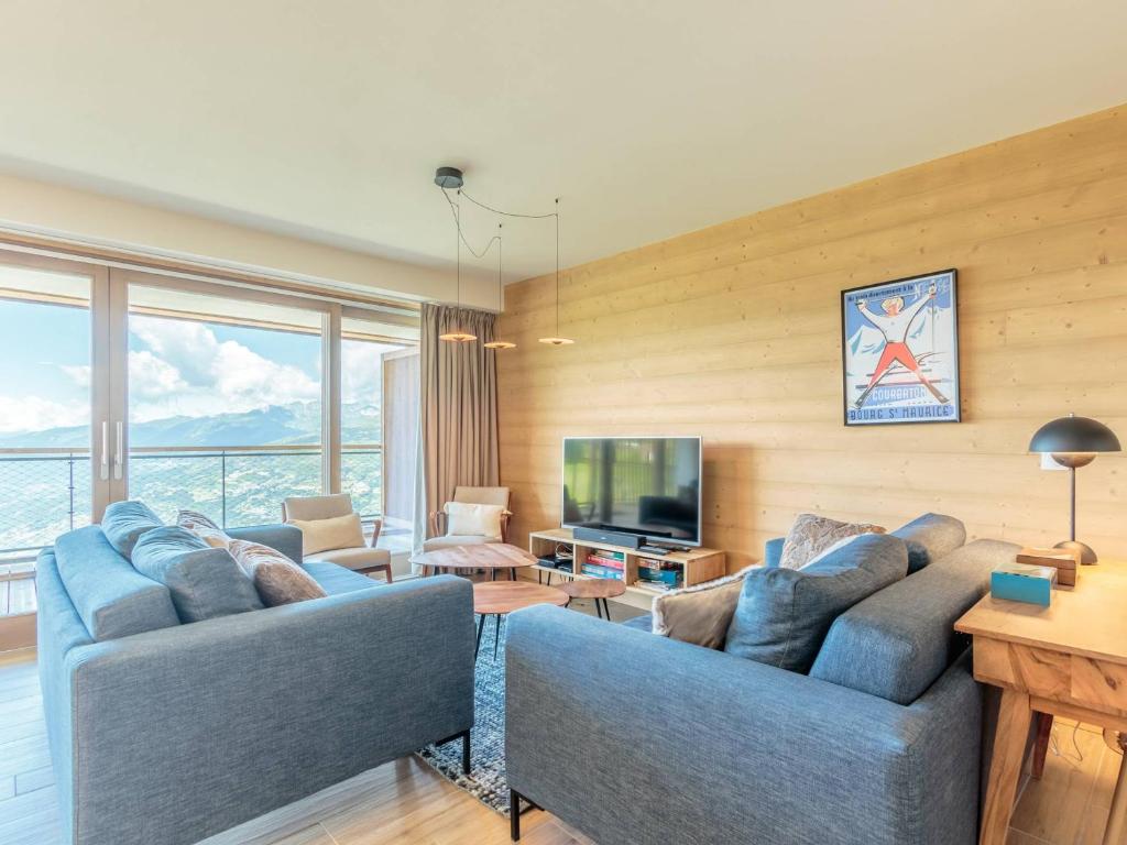 a living room with two blue couches and a television at Duplex 4 pièces Les Arcs 1600, Piscine, SPA, pied de pistes - FR-1-461A-7 in Arc 1600