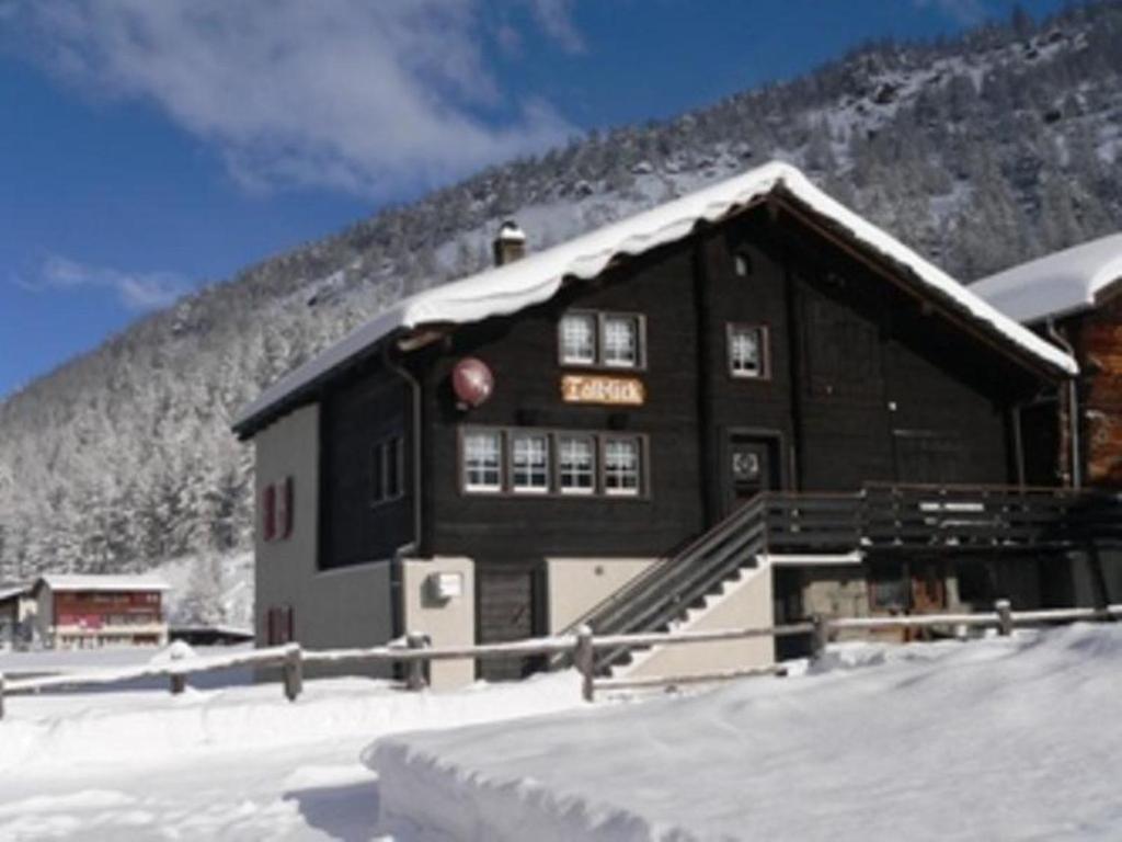 a black building in the snow with a mountain in the background at Apartment Talblick by Interhome in Saas-Grund