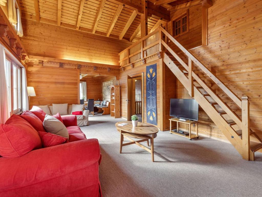 een woonkamer met een rode bank en een trap bij Chalet Arche by Interhome in Wengen