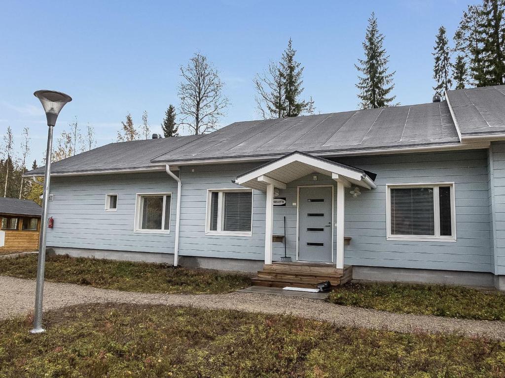 a white house with a porch and a street light at Holiday Home Klz krysoliitti by Interhome in Vuokatti