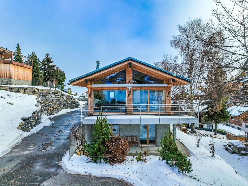 a log home with a wrap around deck in the snow at Chalet Les penguins by Interhome in Nendaz