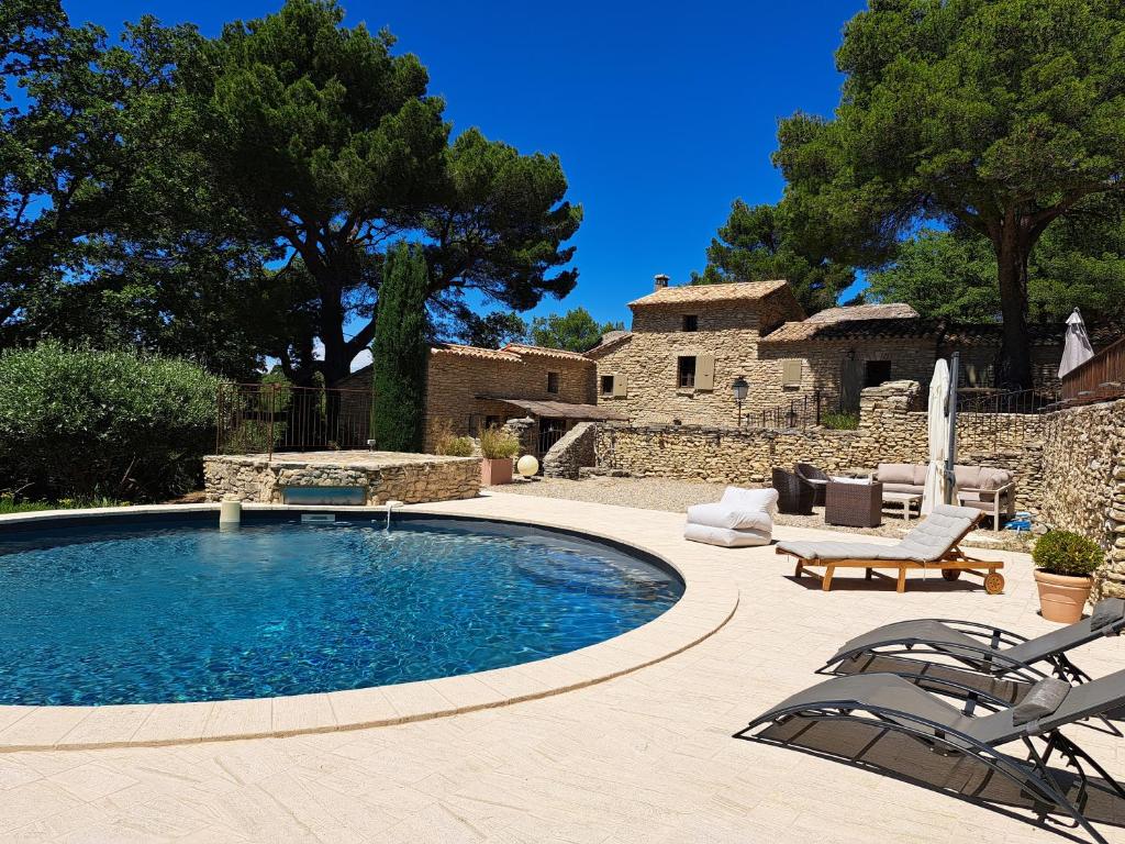 une piscine avec des chaises et une table et une maison dans l'établissement Ancien relais de chasse, isolé en pleine nature provençale 11 couchages, modulable 7, à Saumane-de-Vaucluse