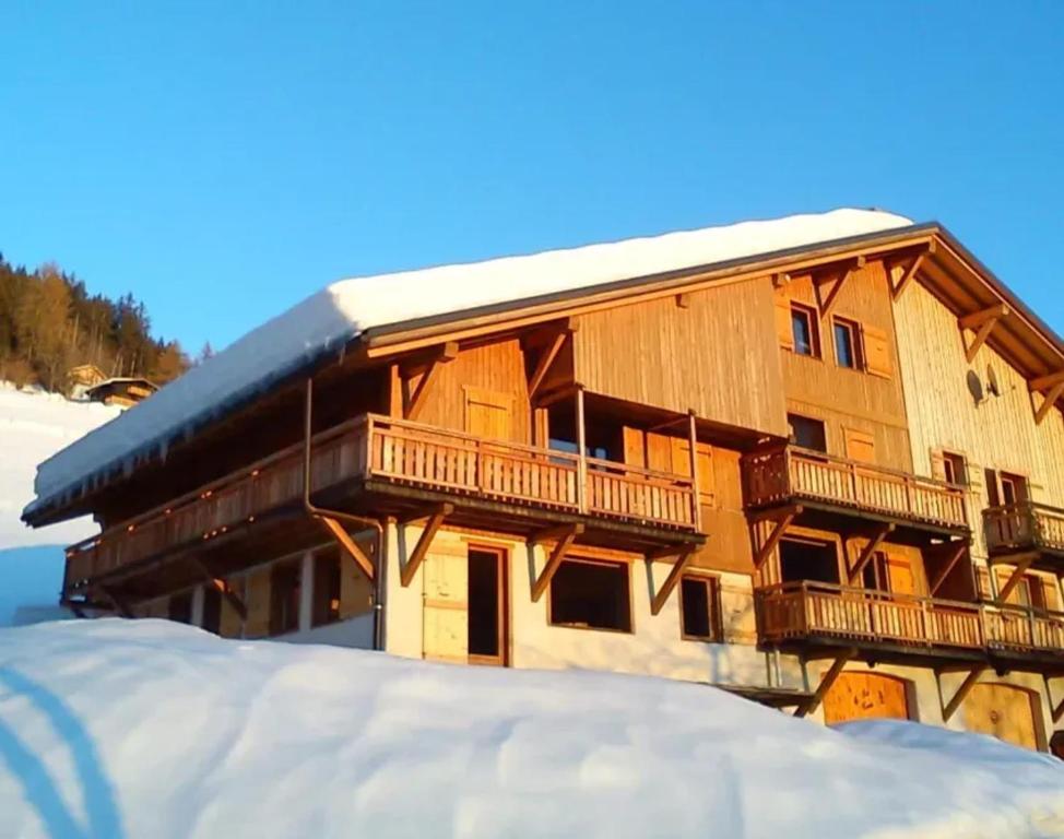 un grand bâtiment en bois avec un balcon dans la neige dans l'établissement Appartement familial à Notre-Dame-de-Bellecombe 80 m² avec jardin, à Notre-Dame-de-Bellecombe