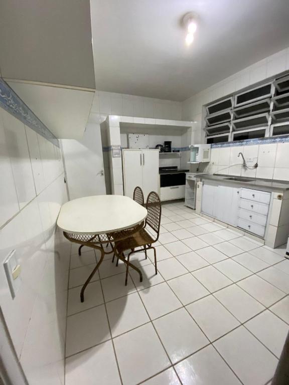 a white kitchen with a table and two chairs at Santorini House in Guarujá