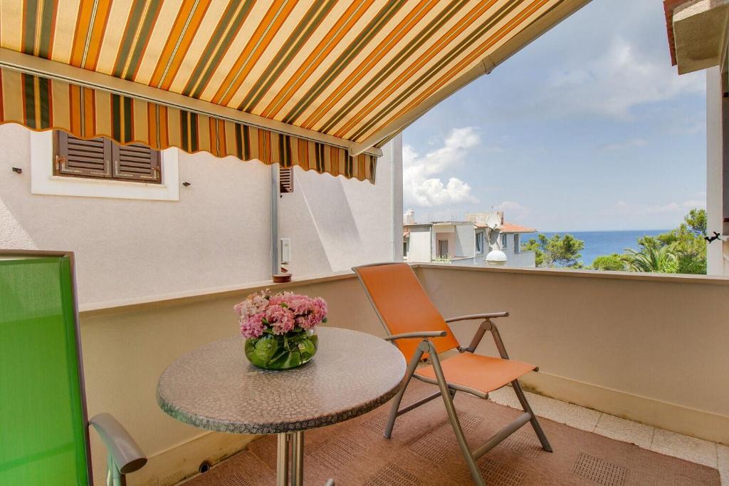 een tafel met een vaas met bloemen op een balkon bij Apartments Eli in Mali Lošinj
