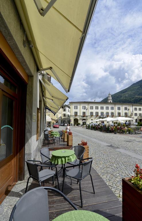 patio ze stołami i krzesłami oraz budynek w obiekcie Albergo Gusmeroli w mieście Tirano