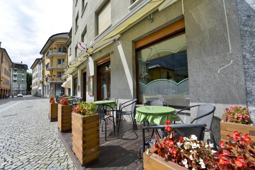 eine Terrasse mit Tischen und Stühlen auf einer Straße in der Unterkunft Albergo Gusmeroli in Tirano