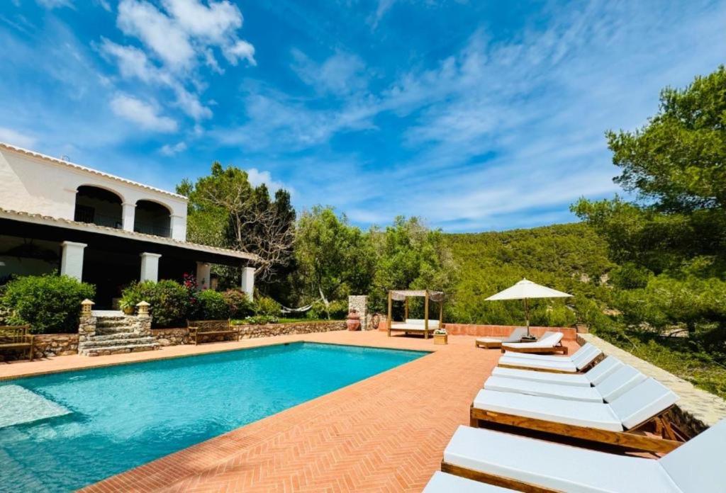 a swimming pool with lounge chairs and a house at Villa Ses Casetes Ibiza in Montecristo