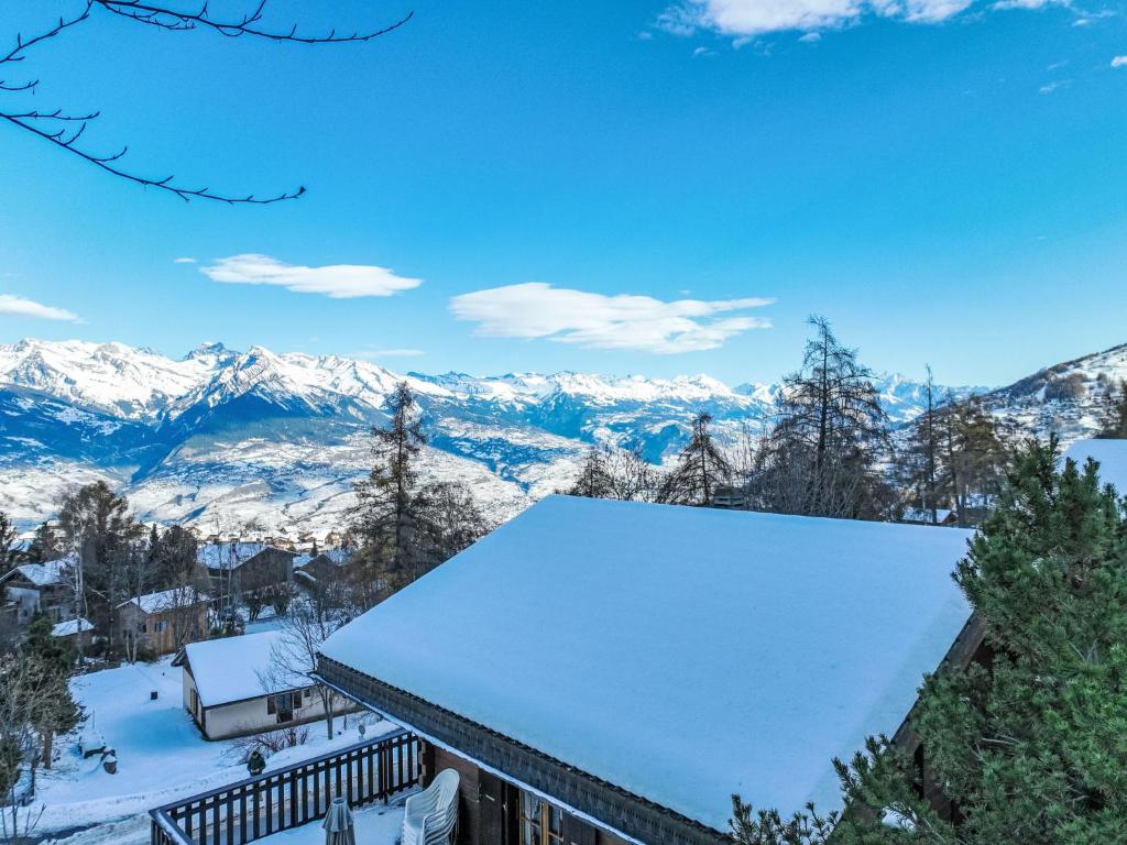 Un techo de un edificio cubierto de nieve con montañas al fondo. en Chalet Ushuaia by Interhome, en Nendaz